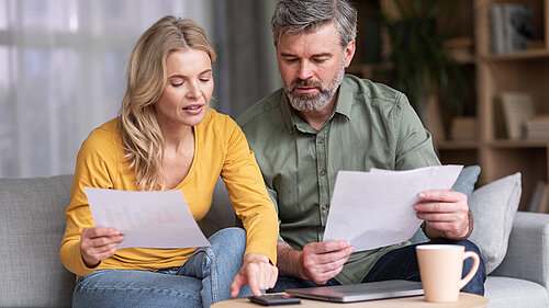 Middle aged husband and wife calculating their budget together.